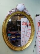A PAIR OF OVAL MIRRORS, THE BEADED AND RIBBON TIED GILT FRAMES NOW SURMOUNTED BY ARRANGEMENTS OF