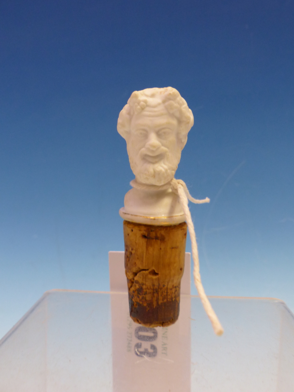 A EUROPEAN BISCUIT PORCELAIN HEAD OF BACCHUS ON A CORK BASE AS A BOTTLE STOPPER. H 8cms.