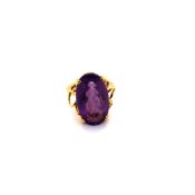 AN OVAL AMETHYST GEMSET RING IN A RAISED FOUR CLAW SETTING. THE MOUNT UNHALLMARKED, STAMPED 750