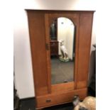 A HEALS OAK WARDROBE WITH ARCHED RECTANGULAR MIRRORED DOOR OVER A DRAWER AND BLADE FEET. W 113 x D