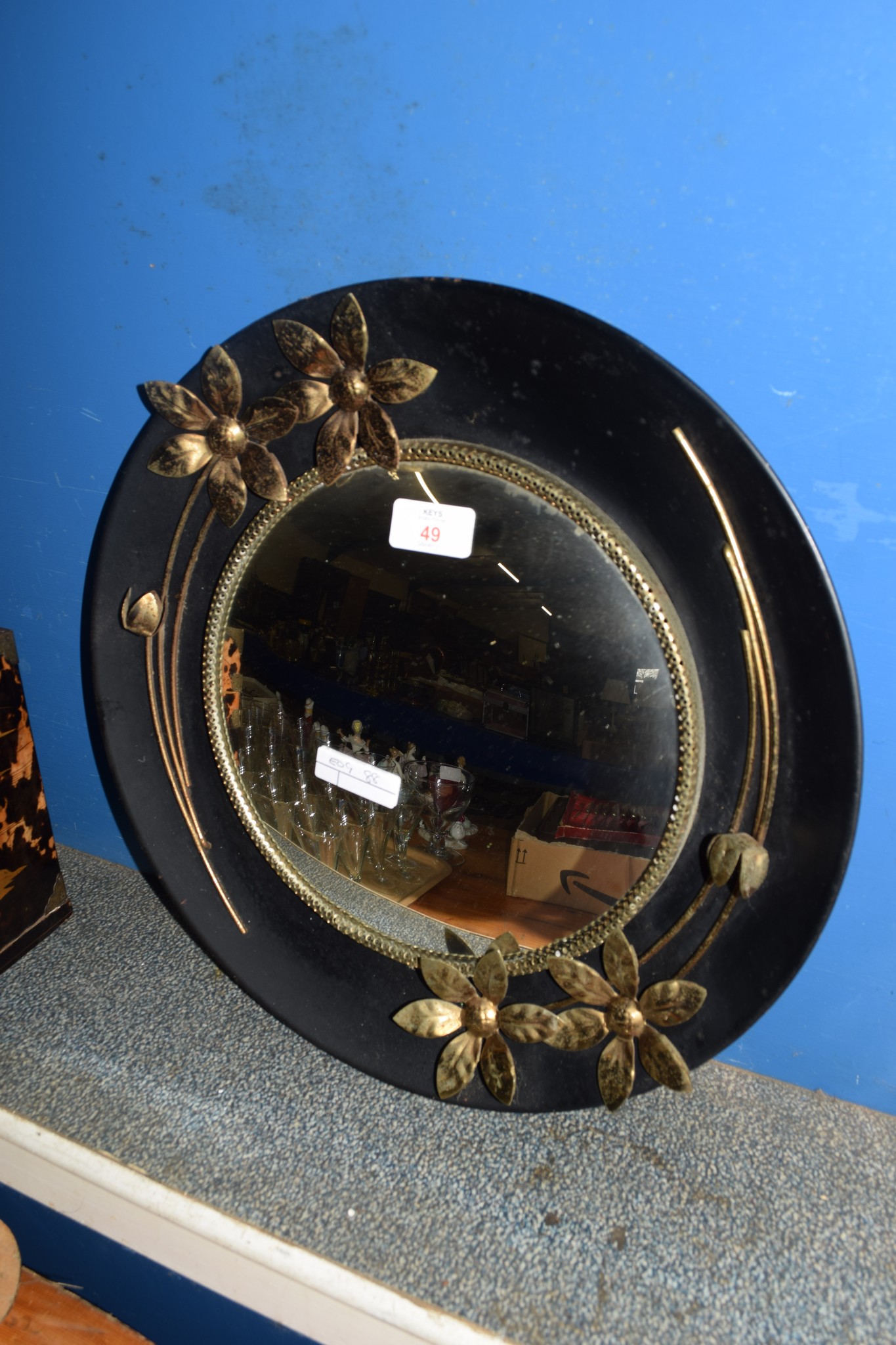 CIRCULAR WALL MIRROR WITH BLACK FRAME AND FLOWERS MODELLED IN RELIEF