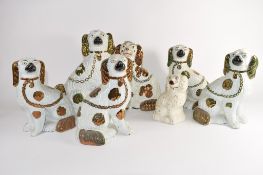 Group of seven Staffordshire dogs all with gilt highlights