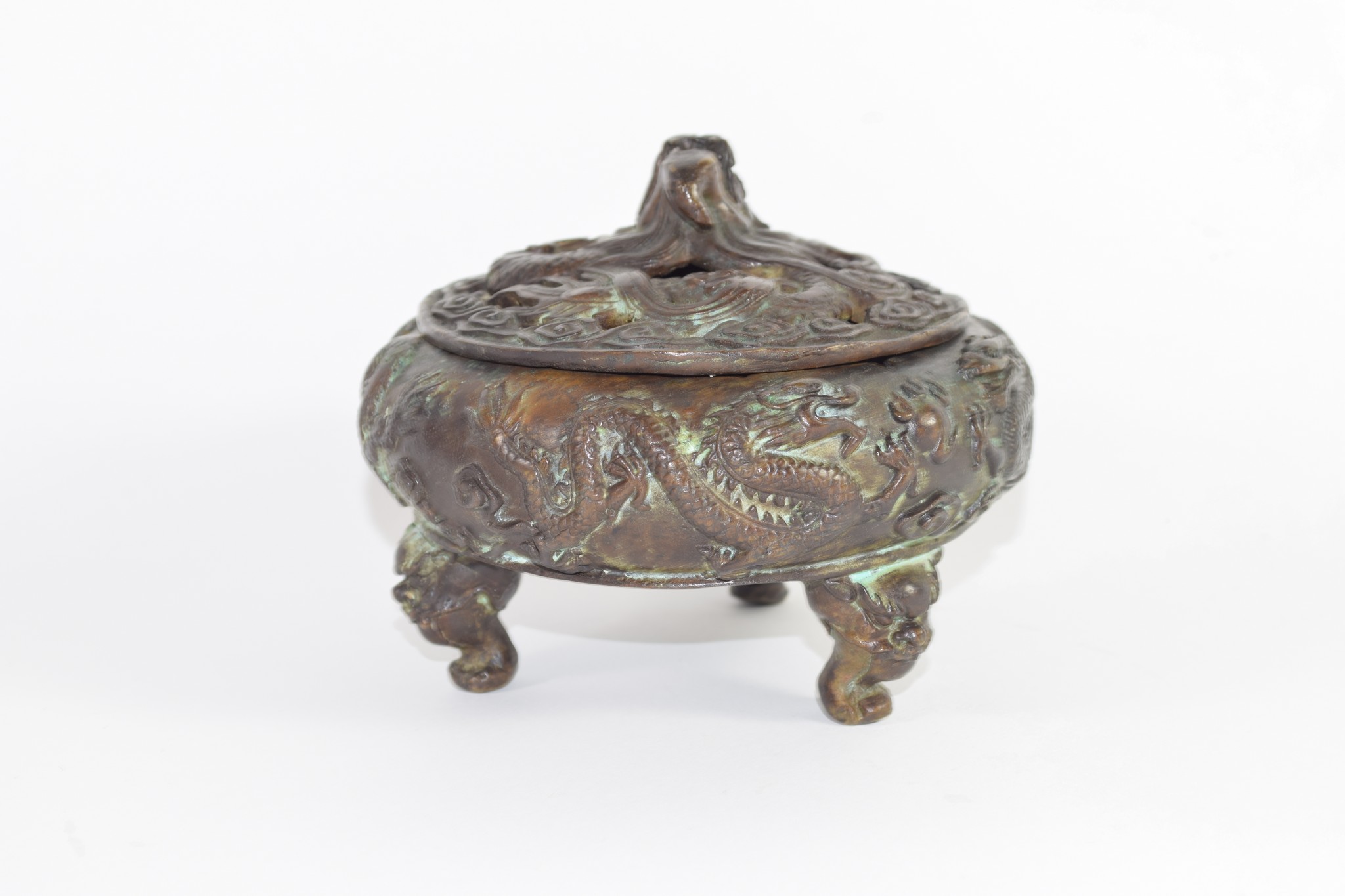 Chinese bronze pot and cover on three feet, modelled in relief with dragons, the cover with