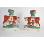 Staffordshire pair of cows with calves modelled as spill holders on oval bases (2)