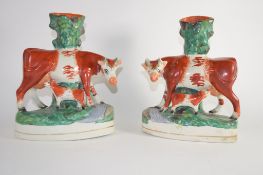 Staffordshire pair of cows with calves modelled as spill holders on oval bases (2)