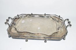 TWO SILVER COLOURED METAL SERVING TRAYS, ONE WITH RAIL AND SMALL STUB FEET