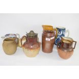 POTTERY JUGS INCLUDING TWO DOULTON HARVESTWARE JUGS, ONE WITH PLATED RIM AND COVER