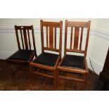 Set of three early 20th century oak, rail back dining chairs with black seats (3)