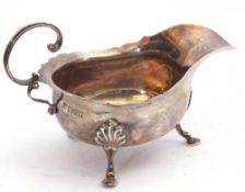 Edward VII silver sauce boat of typical form with card cut rim and applied flying C-scroll handle,