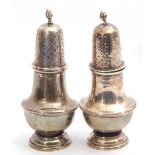 Pair of George V silver peppers having a baluster body, a pierced pull off lid with an urn finial