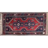 Small 20th century Caucasian wool rug, geometric decoration in red, blue and cream, 130cm x 69cm