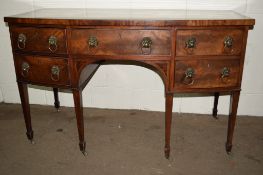 19TH CENTURY BOW FRONT SIDEBOARD RAISED ON TAPERED LEGS OVER CASTERS AND FEATURING MOLDED LIONS HEAD