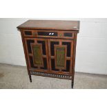 ORIENTAL STYLE SIDE CABINET WITH HEAVILY PANELLED DECORATION AND INSET WITH TWO PICTORIAL BRASS