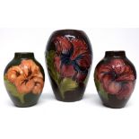 Group of three Moorcroft vases, all with tube lined floral designs on a brown and green ground,