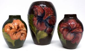 Group of three Moorcroft vases, all with tube lined floral designs on a brown and green ground,