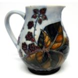 Moorcroft jug with a tube lined design of flowers and berries, 16cm high