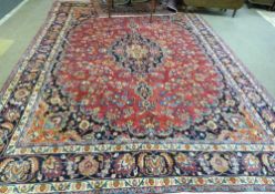 Large Persian Mashad carpet, multi-coloured medallion and floral design to a red ground, 387cm x