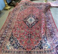 Red ground Persian Kashan carpet, with floral mediallion designs in blue, pink and beige, 290 x