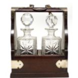 Oak tantalus containing two cut glass decanters and stoppers, the tantalus case with silver metal