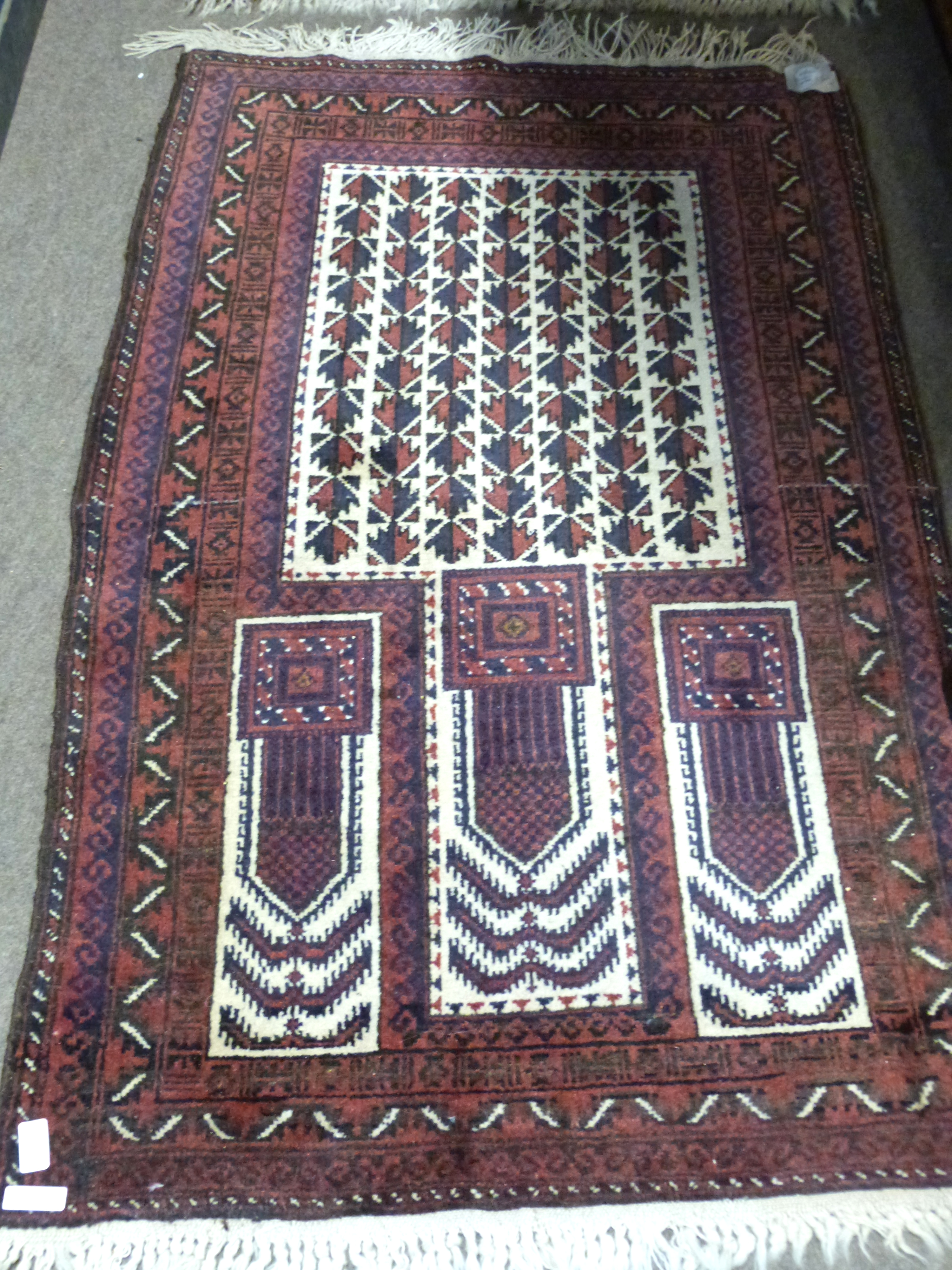 Iranian wool prayer rug with geometric patterns in blue and beige to a dark red ground, 144 x 80cm