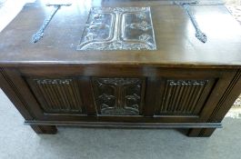 20th century carved oak coffer, the lid with wrought iron strap work and central carved foliate