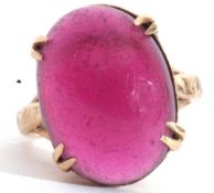 Yellow metal and pink cabochon stone ring, the large pink cabochon four claw set and raised in a