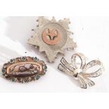 Mixed Lot: three white metal brooches to include a tied ribbon, an oval pierced example with a
