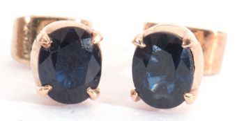 Pair of single stone small sapphire stud earrings in yellow metal mounts and post fittings