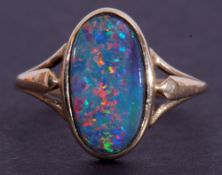 9ct gold and opal ring, the oval shaped opal doublet in rub-over setting and raised between split