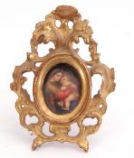 An oval hand painted miniature on porcelain depicting a mother and child in an ornate carved