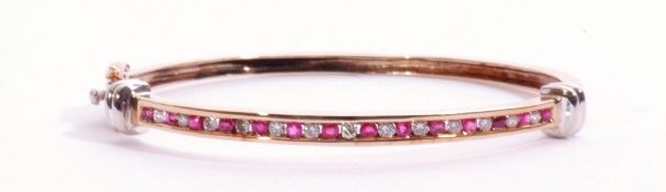 9ct gold ruby and diamond hinged bangle, the top section alternate channel set with 14 round cut