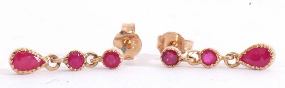 Pair of ruby drop earrings, a design featuring two round cut rubies with an oval ruby
