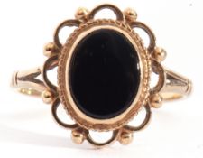 9ct gold and onyx ring, the oval shaped black onyx centre, bezel set and framed in a scrolled bead