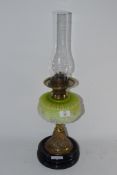 OIL LAMP ON CIRCULAR BLACK BASE WITH GLASS SHADE DECORATED IN RELIEF WITH A FLORAL PATTERN WITH