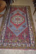 LARGE PATTERNED RUG WITH STYLISED DECORATION DEPICTING STREET SCENES SURROUNDING A CENTRAL PANEL,