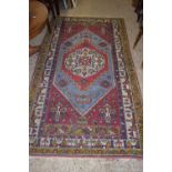 LARGE PATTERNED RUG WITH STYLISED DECORATION DEPICTING STREET SCENES SURROUNDING A CENTRAL PANEL,