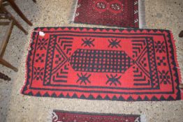 MODERN RUG WITH BLACK GEOMETRIC DESIGNS ON A RED GROUND, APPROX 128 X 62CM