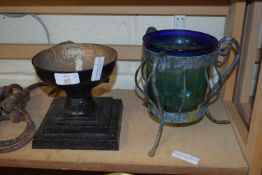 BLACK PAINTED STONE VASE ON SQUARE PLINTH, TOGETHER WITH A GREEN GLASS VASE IN METAL MOUNT