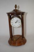 Quartz clock in wooden case, supported by four wooden pillars, with brass acorn knop, 27cm high