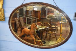 Early 20th century oval bevelled mirror within a carved frame, approx 95 x 64cm