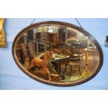 Early 20th century oval bevelled mirror within a carved frame, approx 95 x 64cm