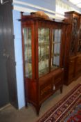 An impressive Art Nouveau display cabinet with leaded and stained glass doors raised above two