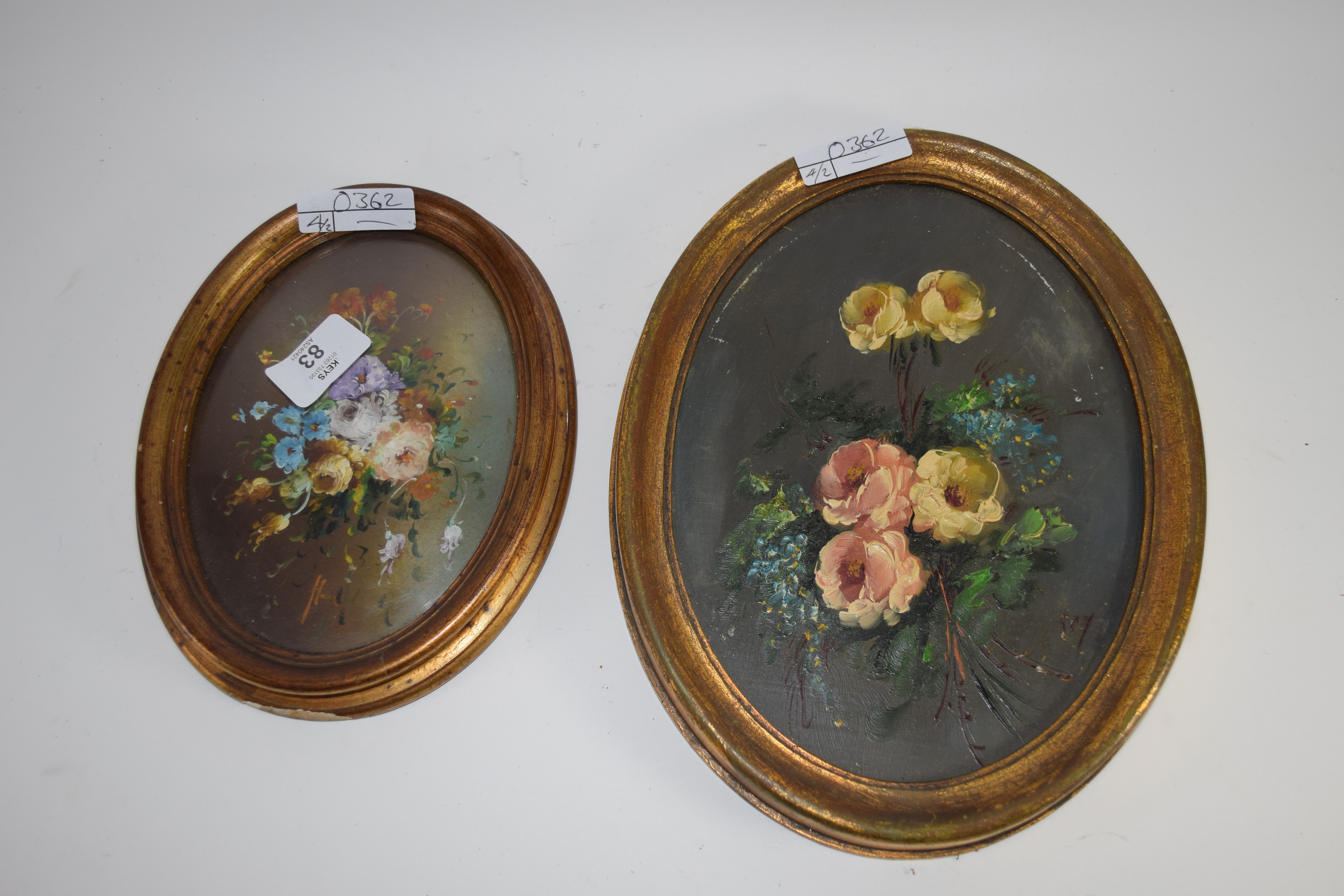 Two paintings of flowers in oval wooden frames
