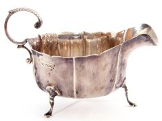 George V silver sauce boat with card cut rim and leaf capped flying handle, the body with a ribbed