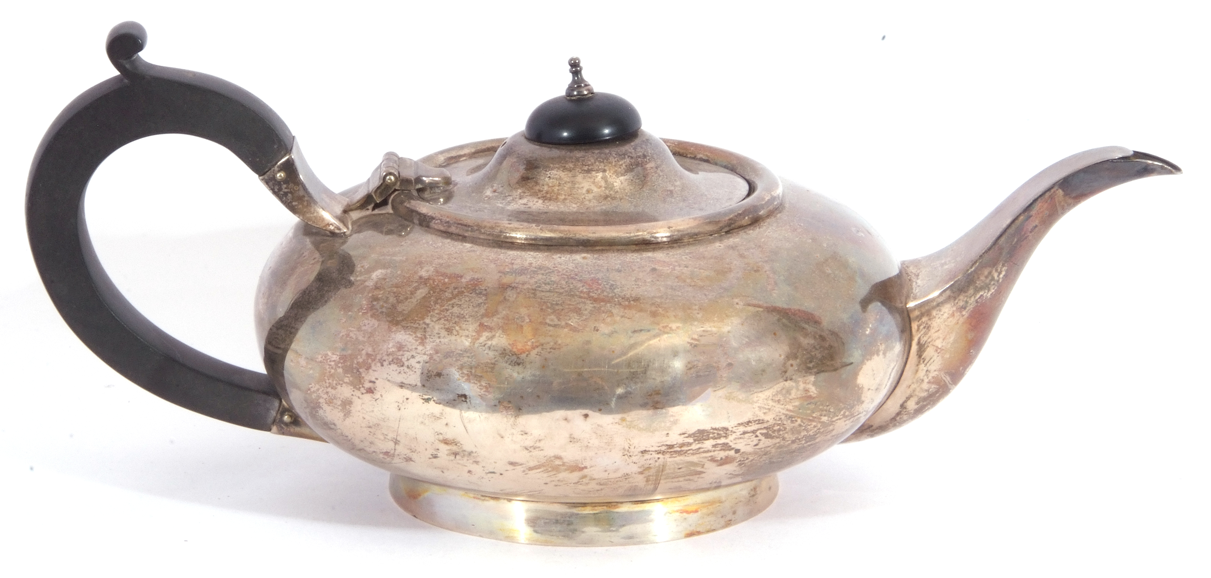 George V silver tea pot of compressed circular form on a spreading foot, ebonised and urn finial,