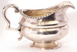 George IV silver cream jug, circular lobed form with gadrooned rim, capped leaf scroll handle on a