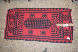 MODERN RUG WITH BLACK GEOMETRIC DESIGNS ON A RED GROUND, APPROX 128 X 62CM