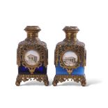 Two Palais Royale gilt metal mounted glass square scent bottles with pierced sleeves and caps