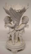 Late 19th century Continental bisque porcelain flower vase, the vase supported by two winged cherubs