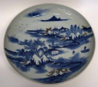 Large Oriental charger or dish decorated in underglaze blue with a mountain and river scene, 38cm